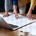 People discussing blueprints at a table